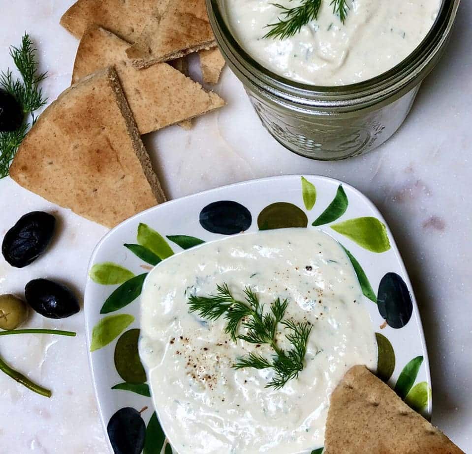 Tzatziki sauce in serving bowl with olives and bread.