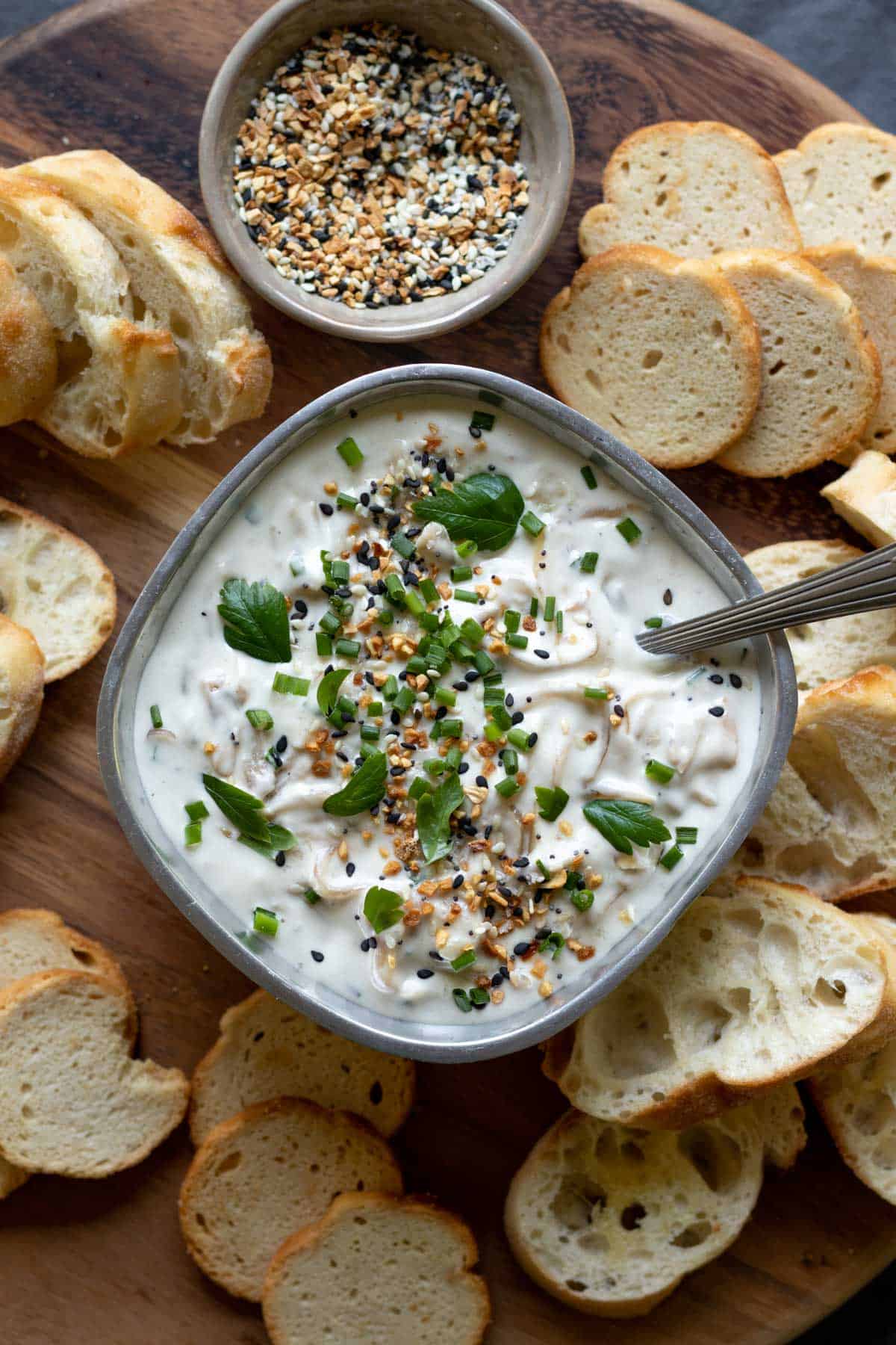 Onion dip in serving bowl surrounded by sliced bread.