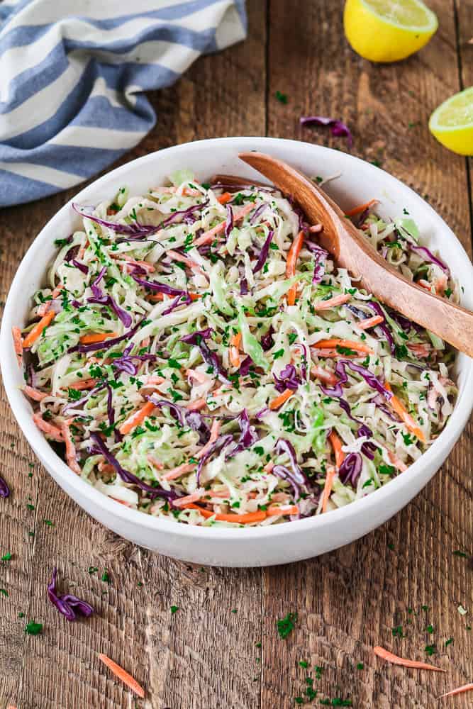 Vegan  coleslaw in bowl with serving spoon.