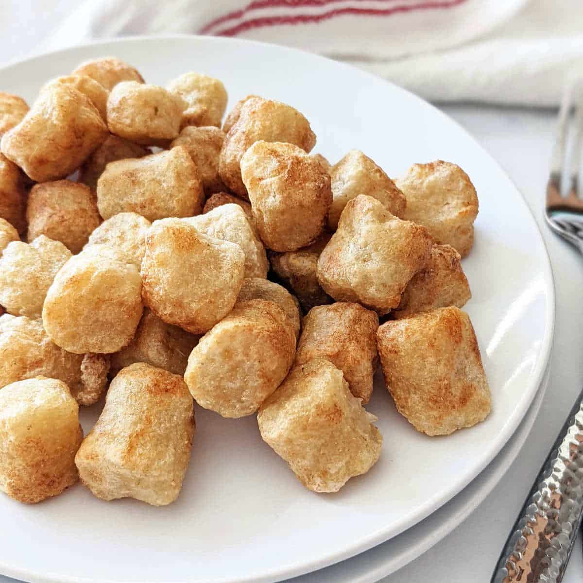 Golden air fried gnocchi piled on a plate.