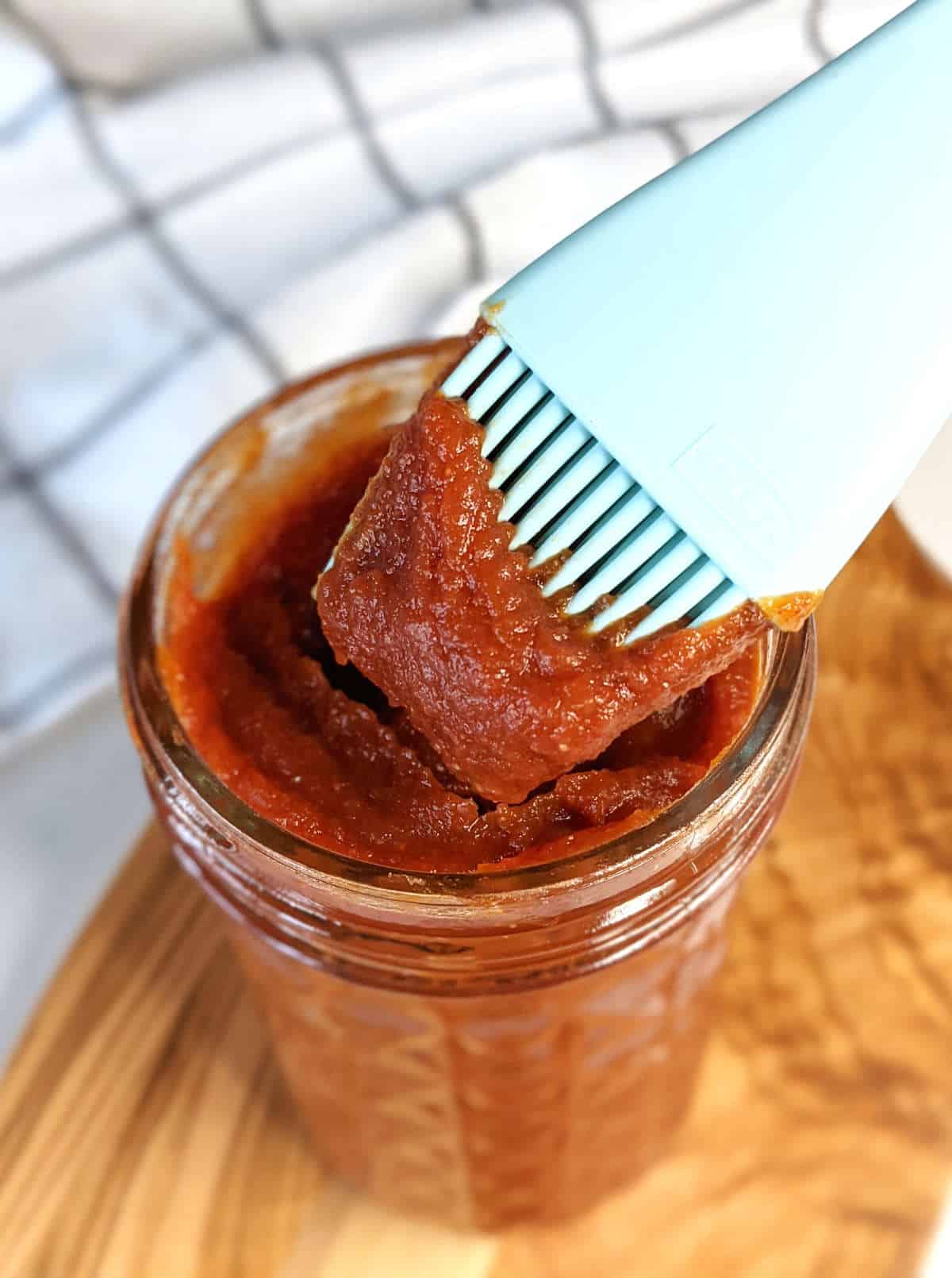 Vegan BBQ sauce in a jar with a basting brush.