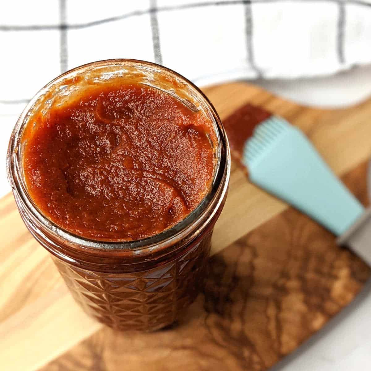 Vegan bbq sauce in a jar on a cutting board.