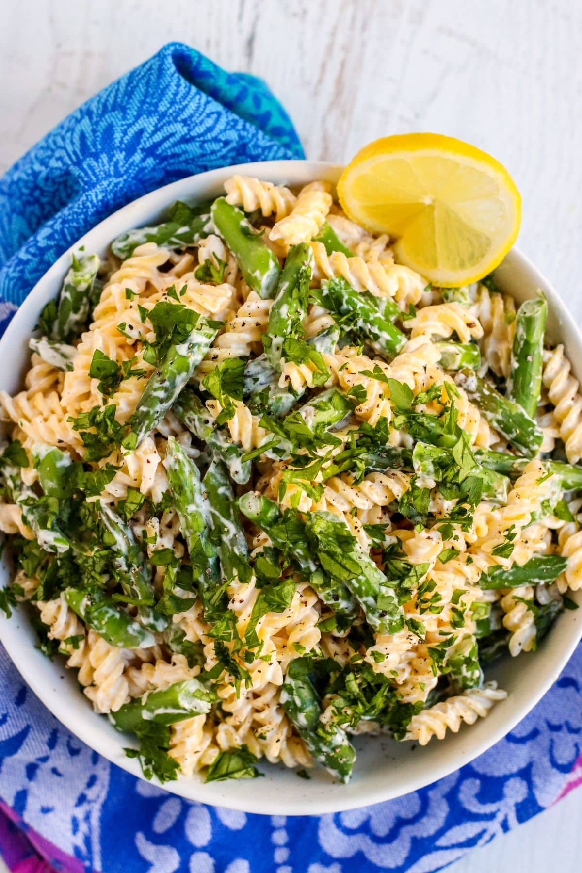 Pasta with asparagus in a large bowl served with a lemon slice on the side.