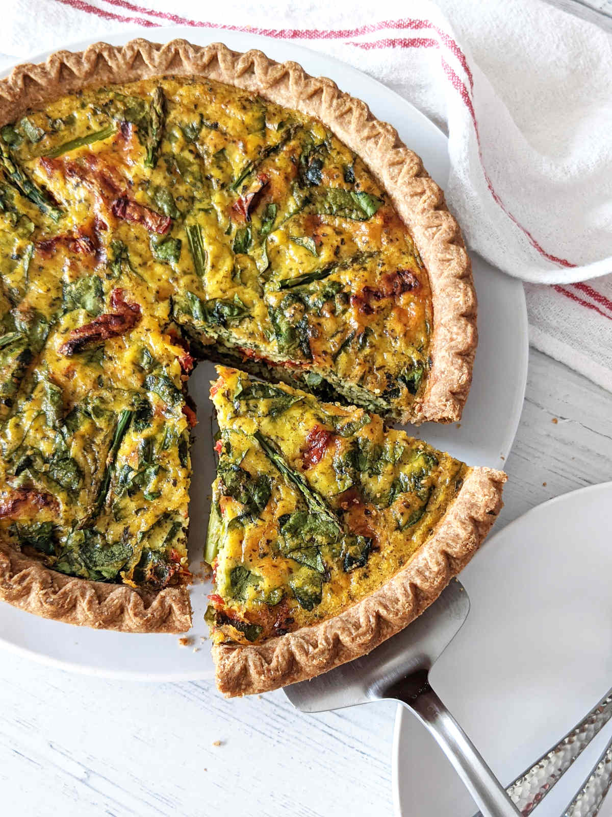 Baked vegan quiche with a slice being removed.