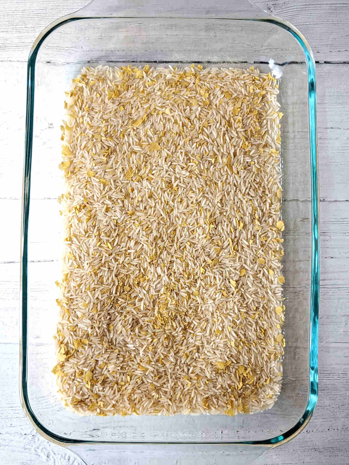 Basmati rice mixed with seasonings in a casserole dish.