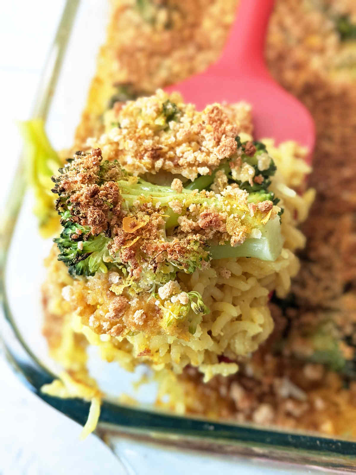 A spatula scooping the broccoli rice casserole out of the baking dish.