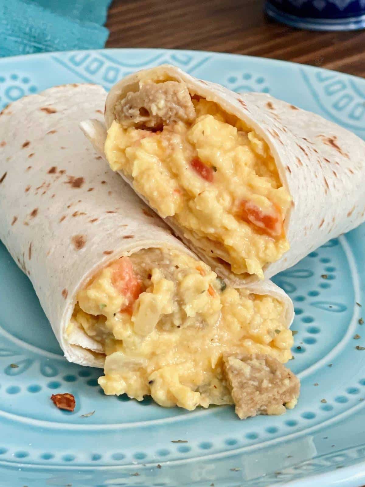 Breakfast burrito cut in half on a plate.