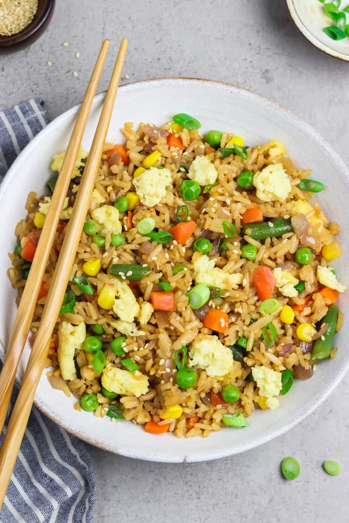 Bowl of fried rice with vegan egg and chopsticks laying across it.