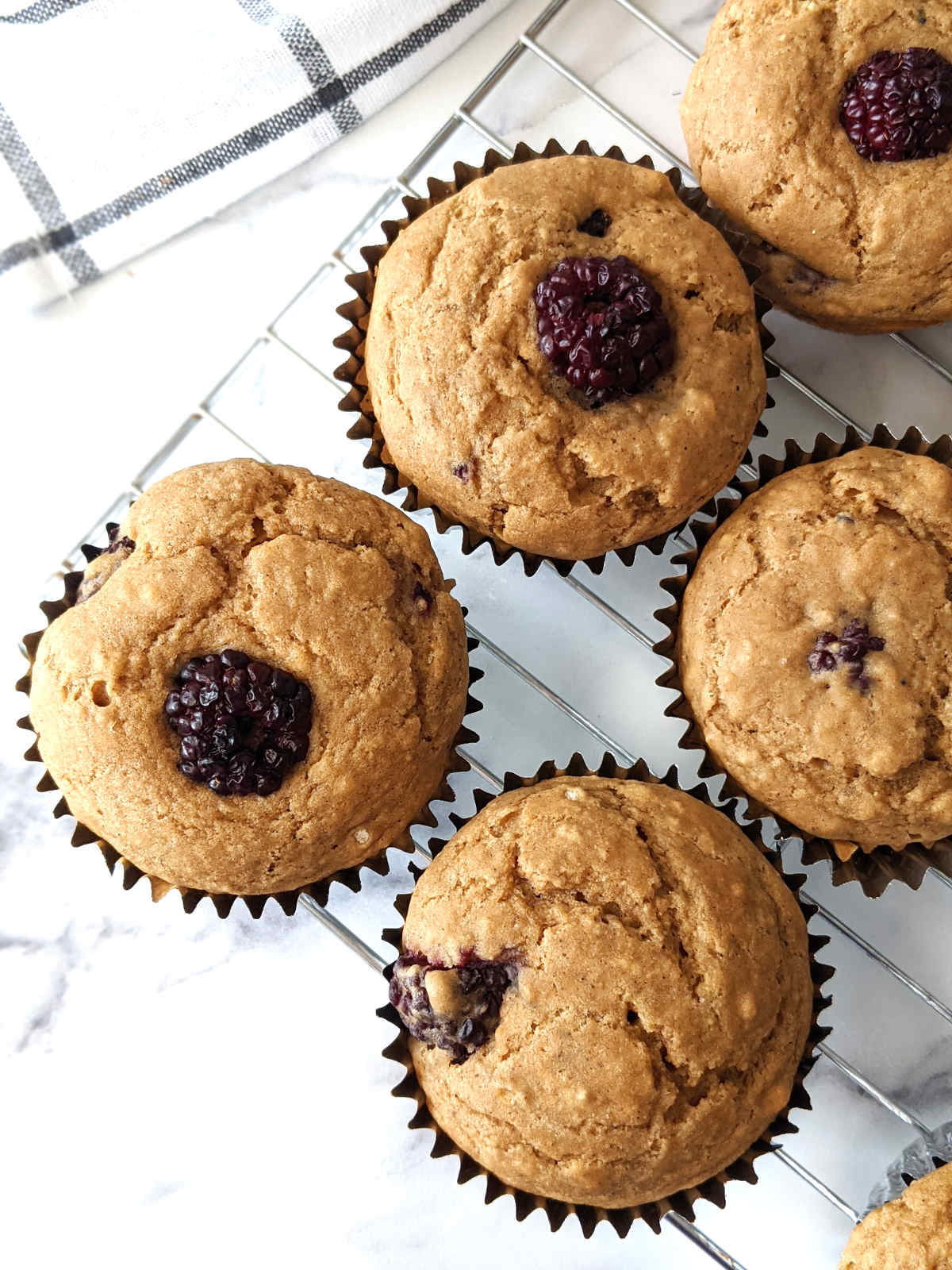 Vegan blackberry muffins sitting on a cooling rack.