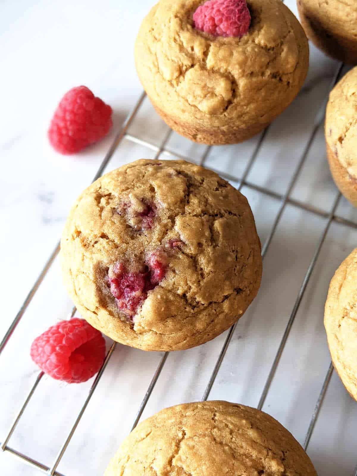 Lemon raspberry vegan muffins sitting on a cooling rack.