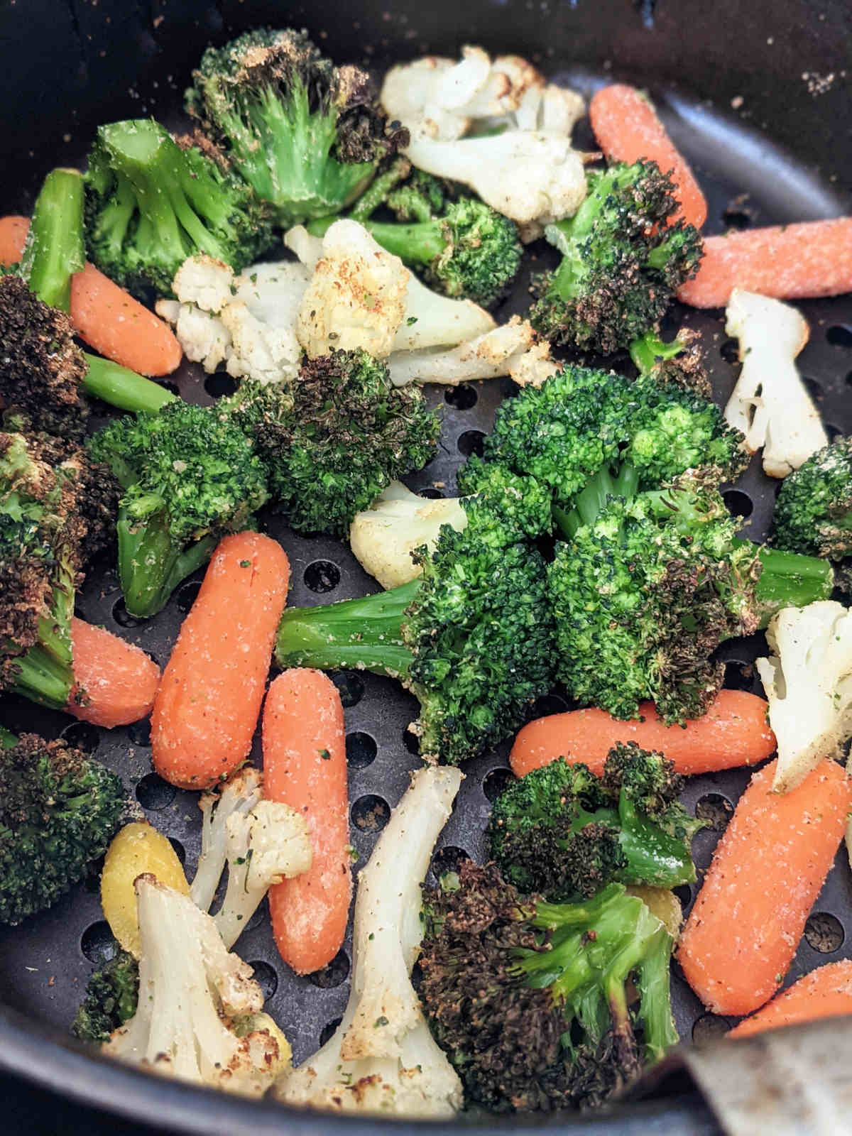 Air fried frozen mixed vegetables in air fryer basket.