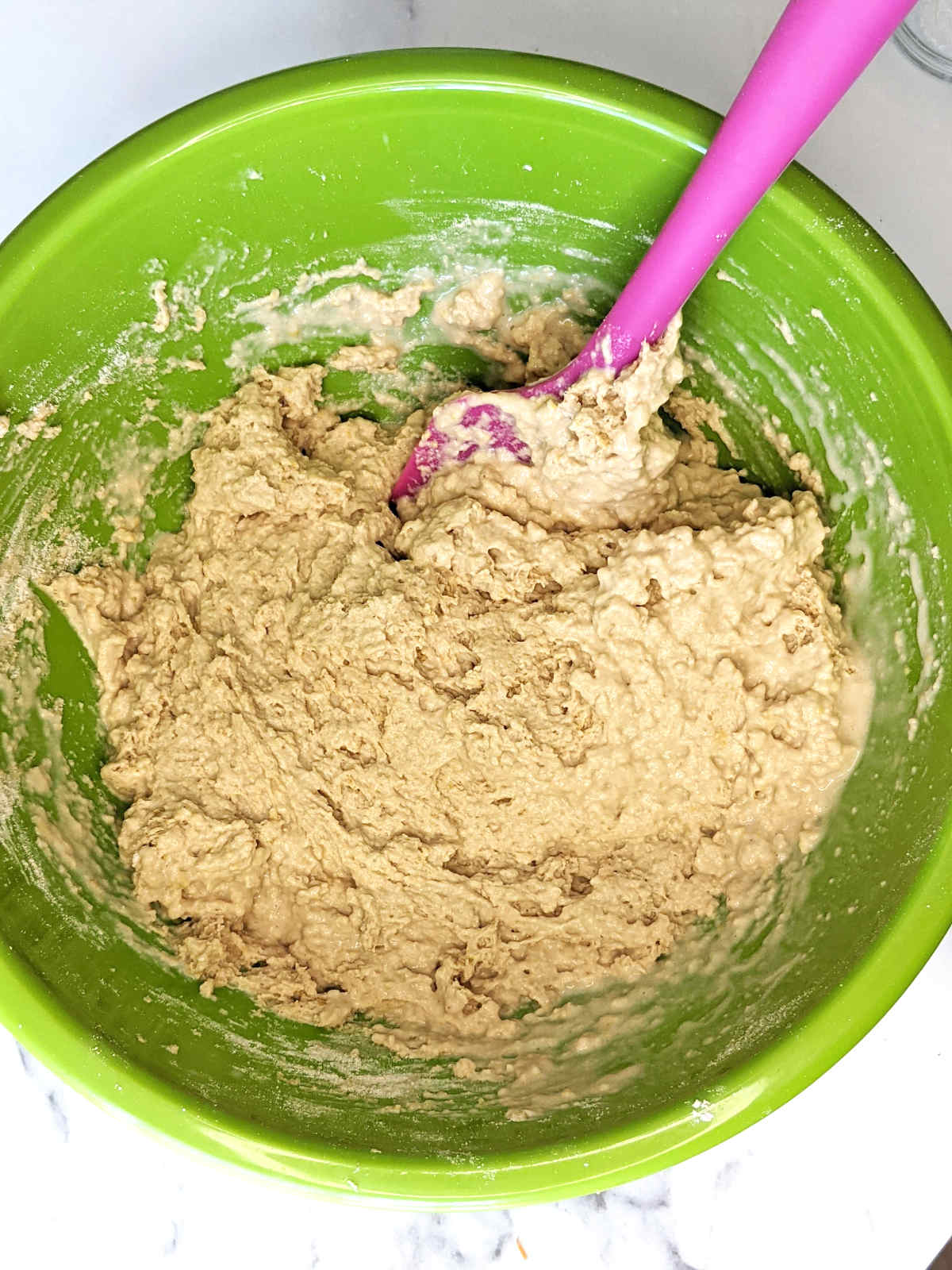 Savory vegan muffin batter in green mixing bowl mixed together before adding vegetables.