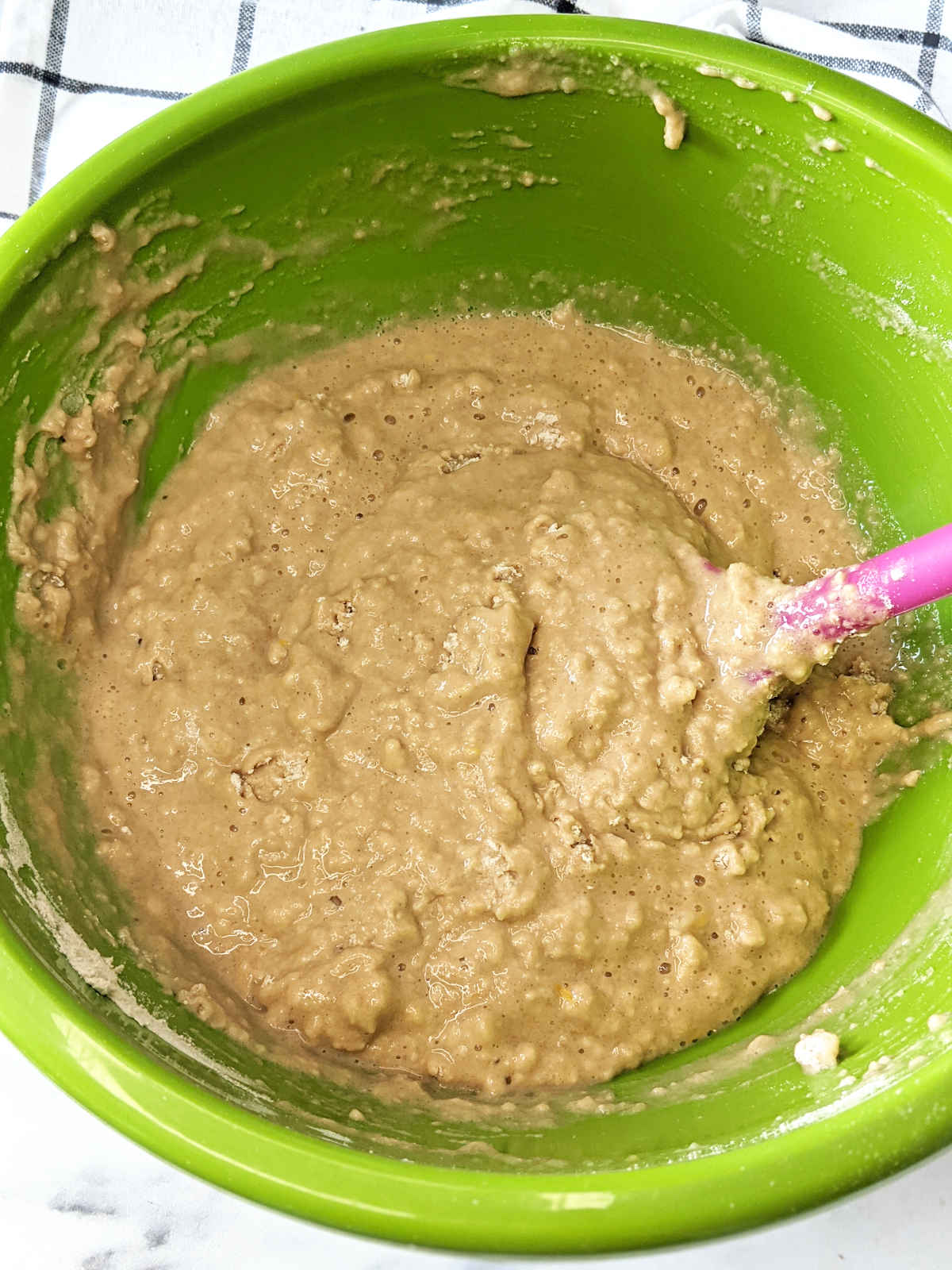Wet ingredients for vegan muffins mixed into the dry in a large mixing bowl.