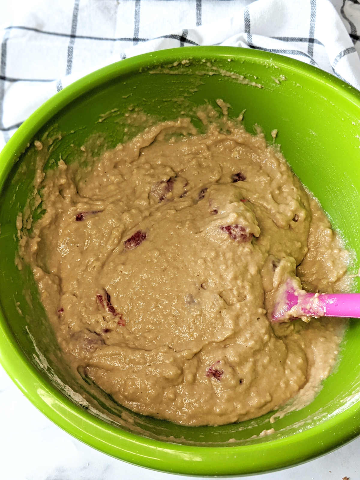 Raspberries mixed into the muffin batter in a large bowl.