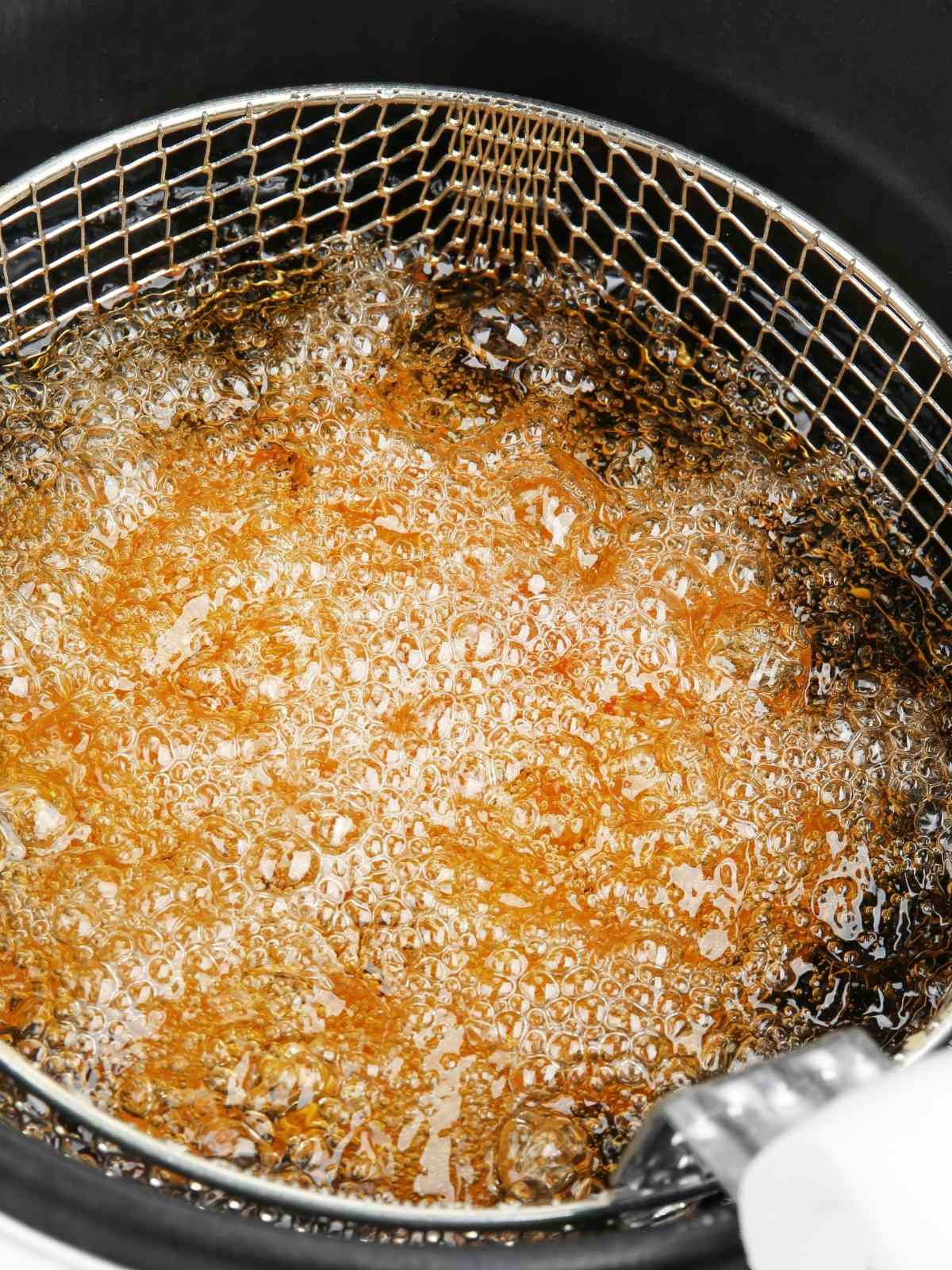 Deep fry bubbling with oil as it cooks french fries.