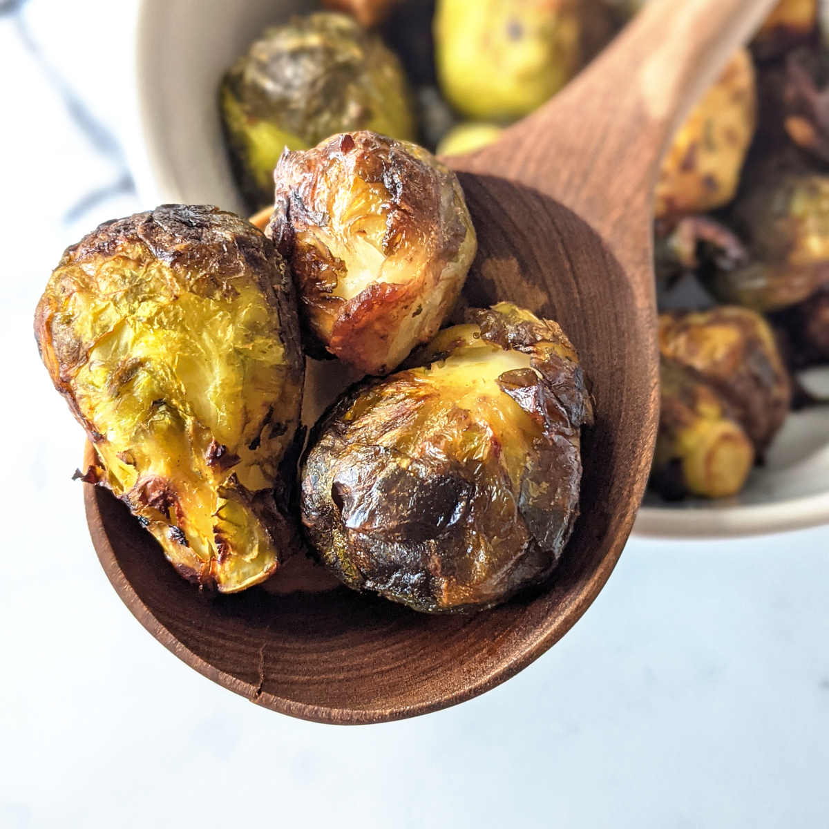 Wooden spoon holding a few roasted brussels sprouts.
