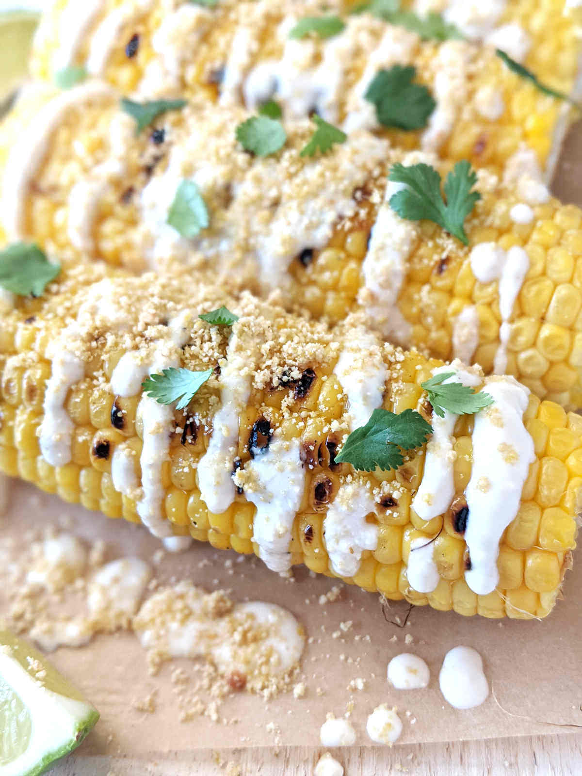 Vegan elote covered in all the toppings sitting on a cutting board.