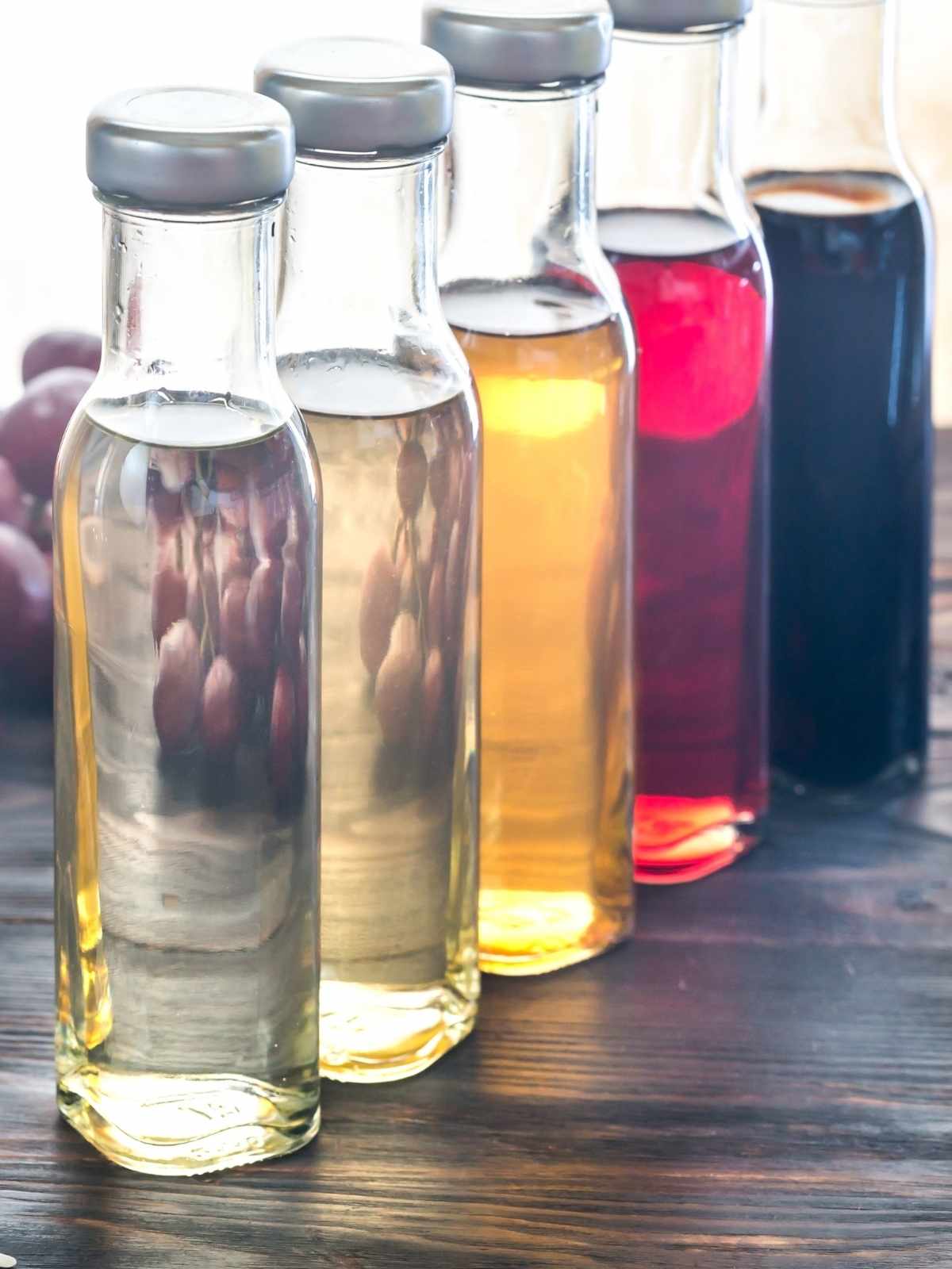 Fruit infused vinegars in glass bottles in a row.