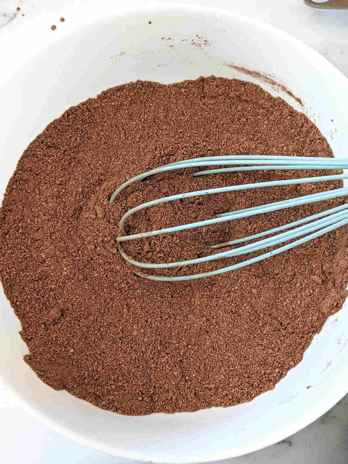 Dry ingredients for gluten free vegan chocolate cupcakes in a large mixing bowl mixed together with a whisk.