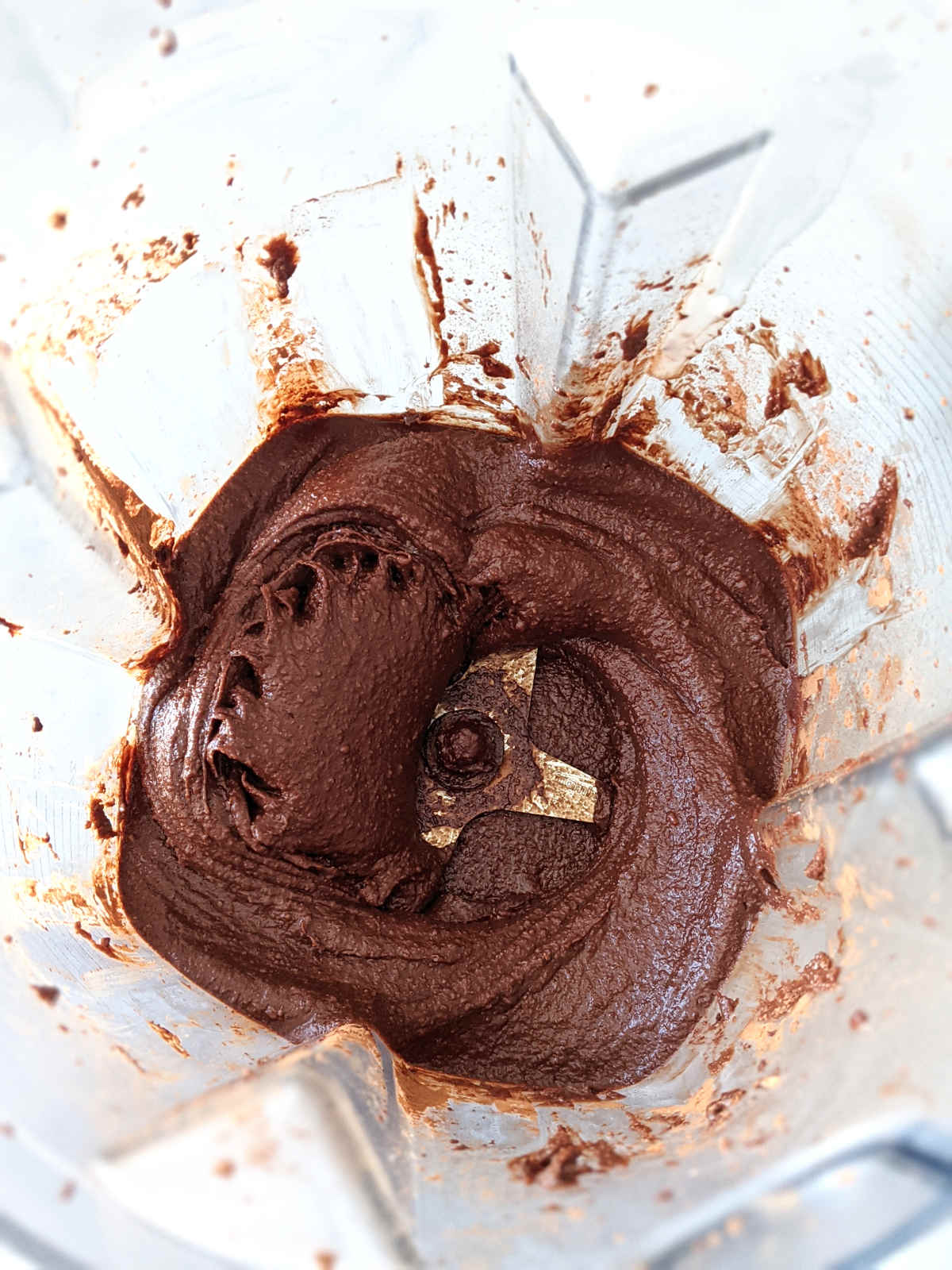 The inside of a blender with vegan chocolate frosting blended smooth.