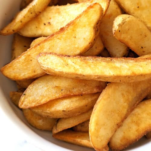 Cooked air fryer frozen potato wedges in a bowl.