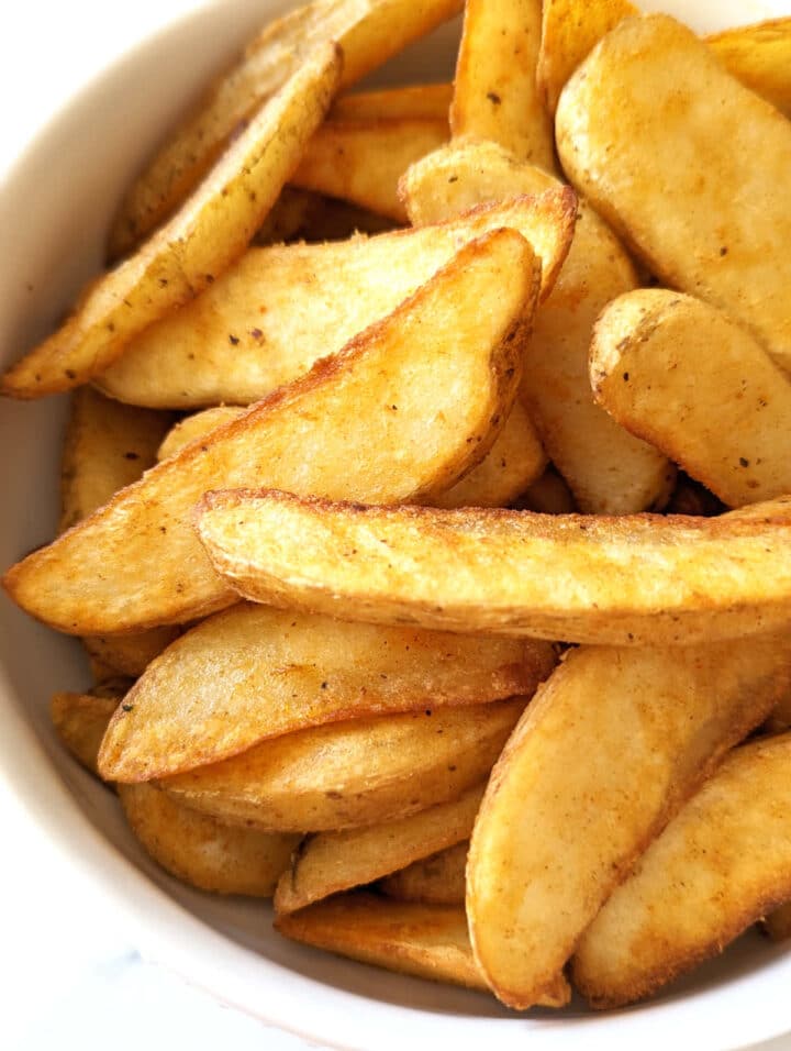 Cooked air fryer frozen potato wedges in a bowl.