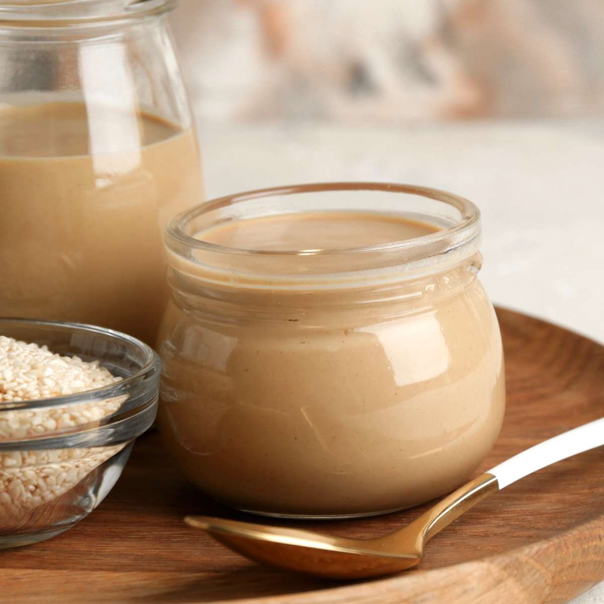 Glass jar of tahini with a spoon.