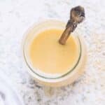Tahini in a glass jar with a spoon.