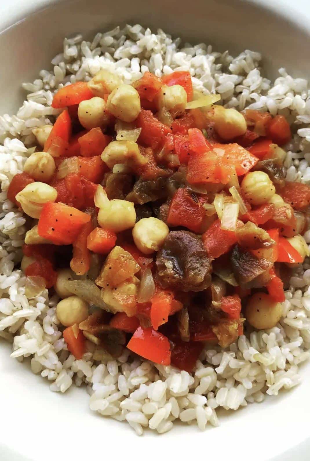 Bowl filled with rice and topped with vegetarian stew.