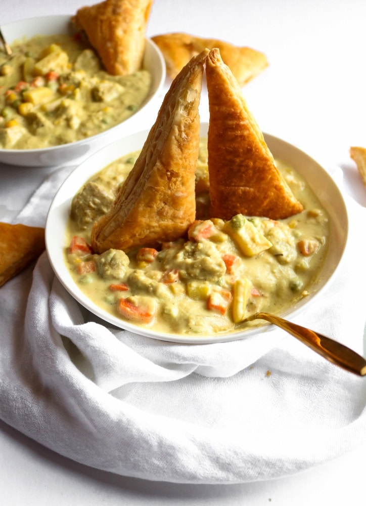 Two bowls of vegan chicken stews topped with rustic bread.