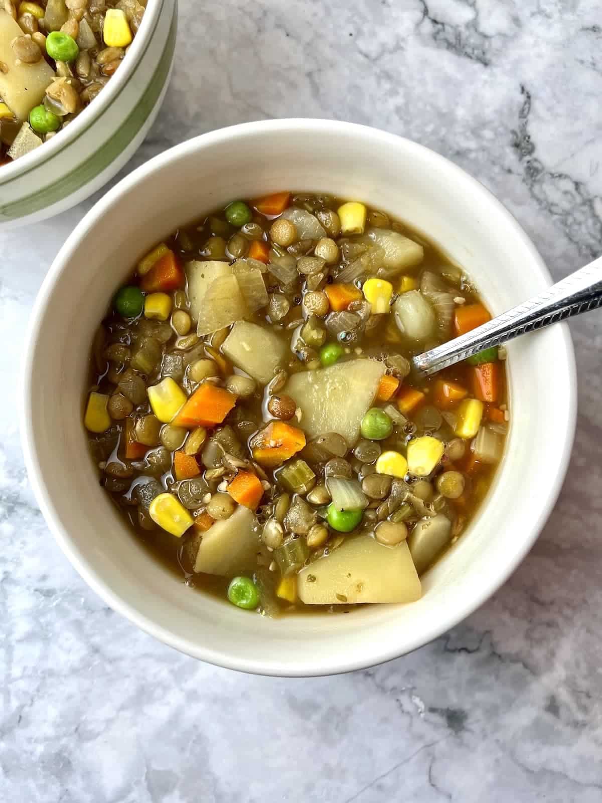 Bowl of lentil potato stew with a spoon.