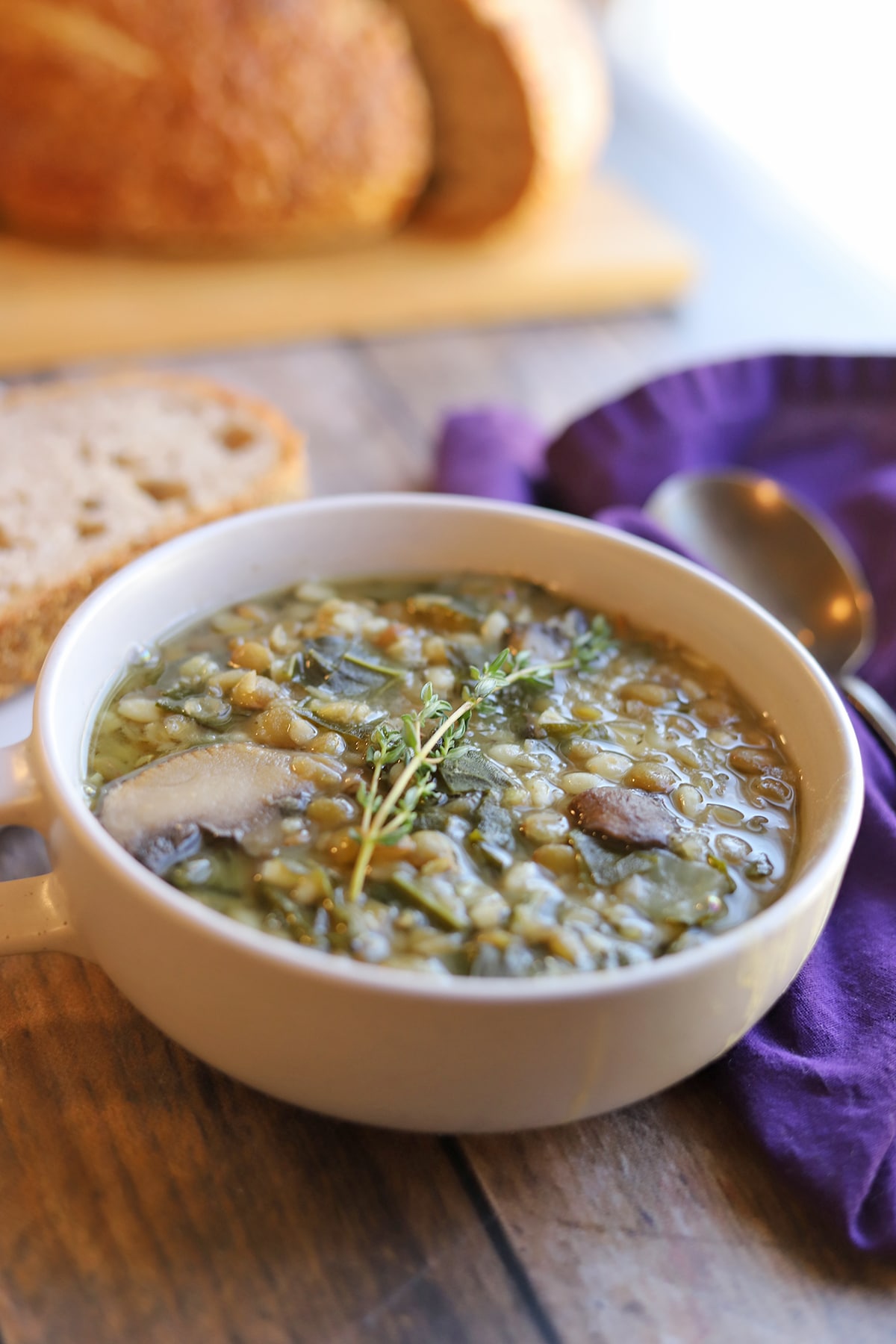 Bowl of lentil mushroom barley stew served with bread on the side.