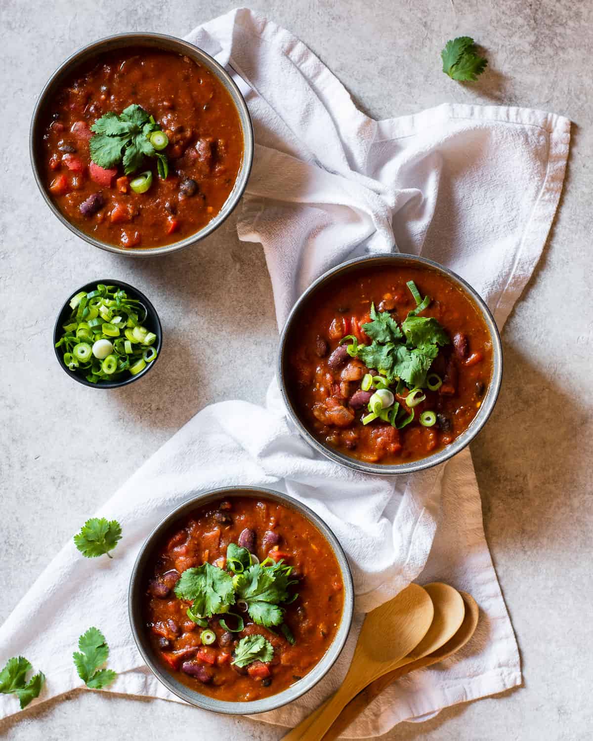 Three bowls of pumpkin veggie stew topped with fresh cilantro and green onion.