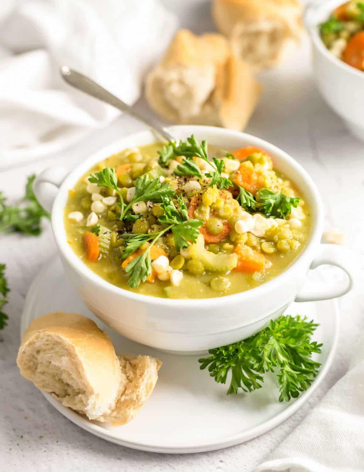 Bowl of split pea sweet potato stew topped with fresh parsley and served with a slice of bread.