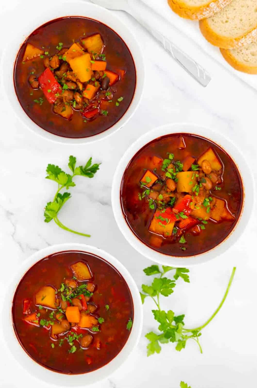 Three bowls of vegan Hungarians Goulash with fresh herbs.