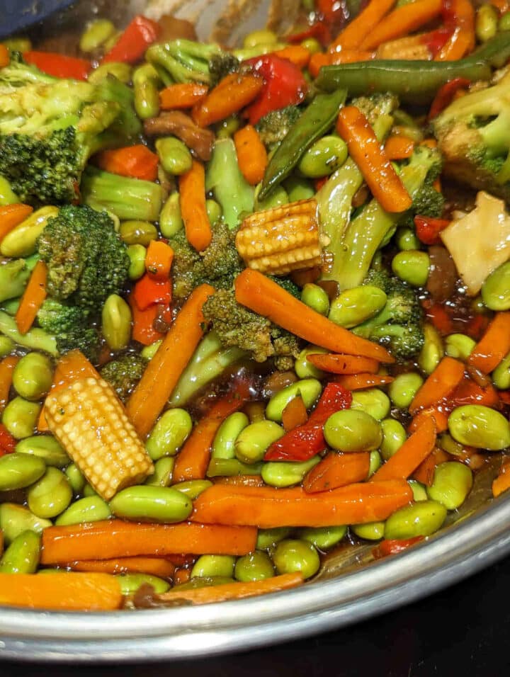 Vegetables in a pan after the vegan stir fry sauce has thickened and coats the veggies.