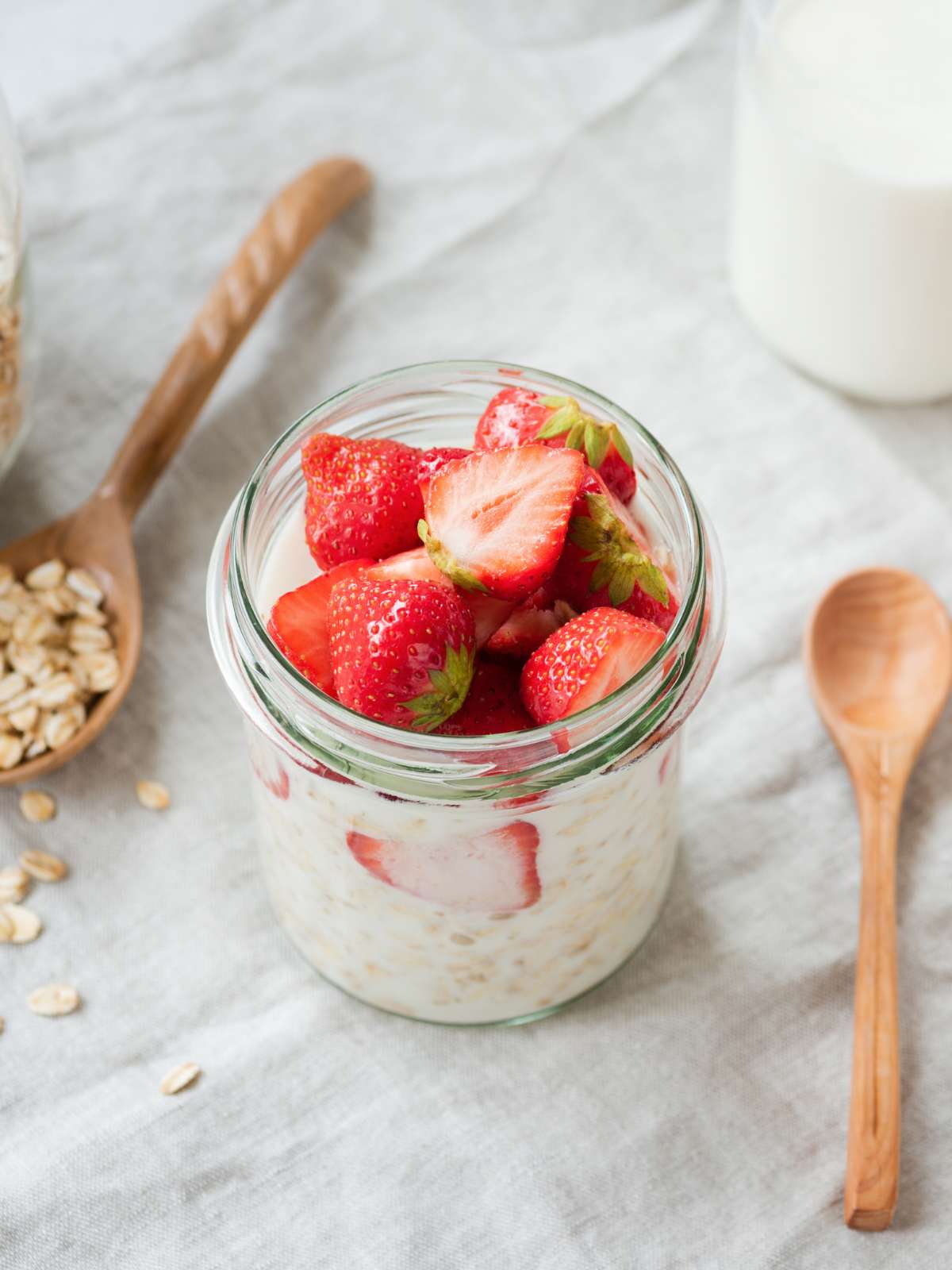 Mason jar full of protein overnight oats and topped with fresh strawberries.