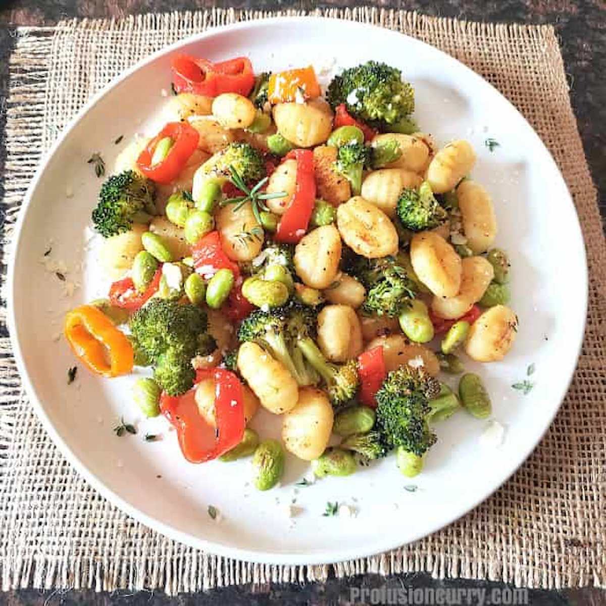 A plate with veggies and gnocchi.