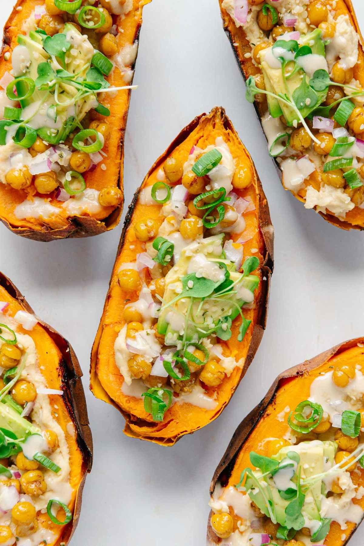 Roasted sweet potato halves topped with veggies and creamy dressing.