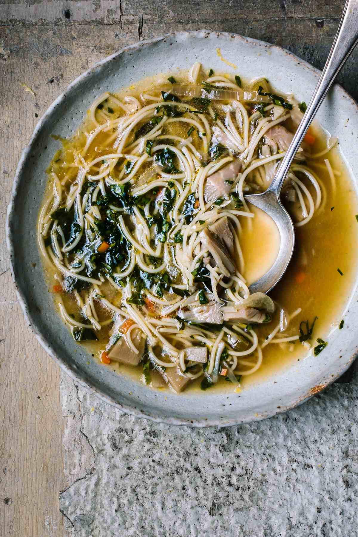 Bowl of vegan chicken noodle soup with a spoon.