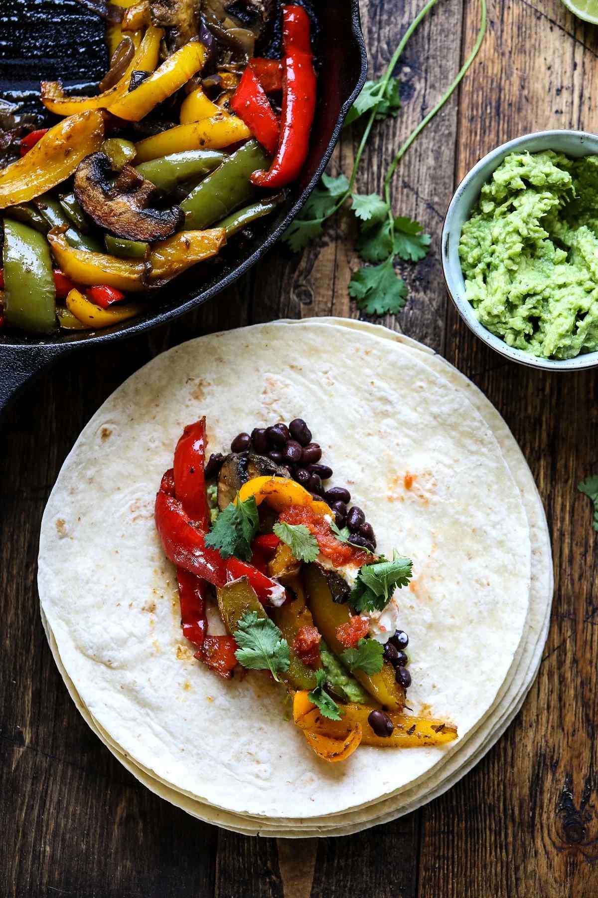 Plate with a tortilla topped with fajita veggies.