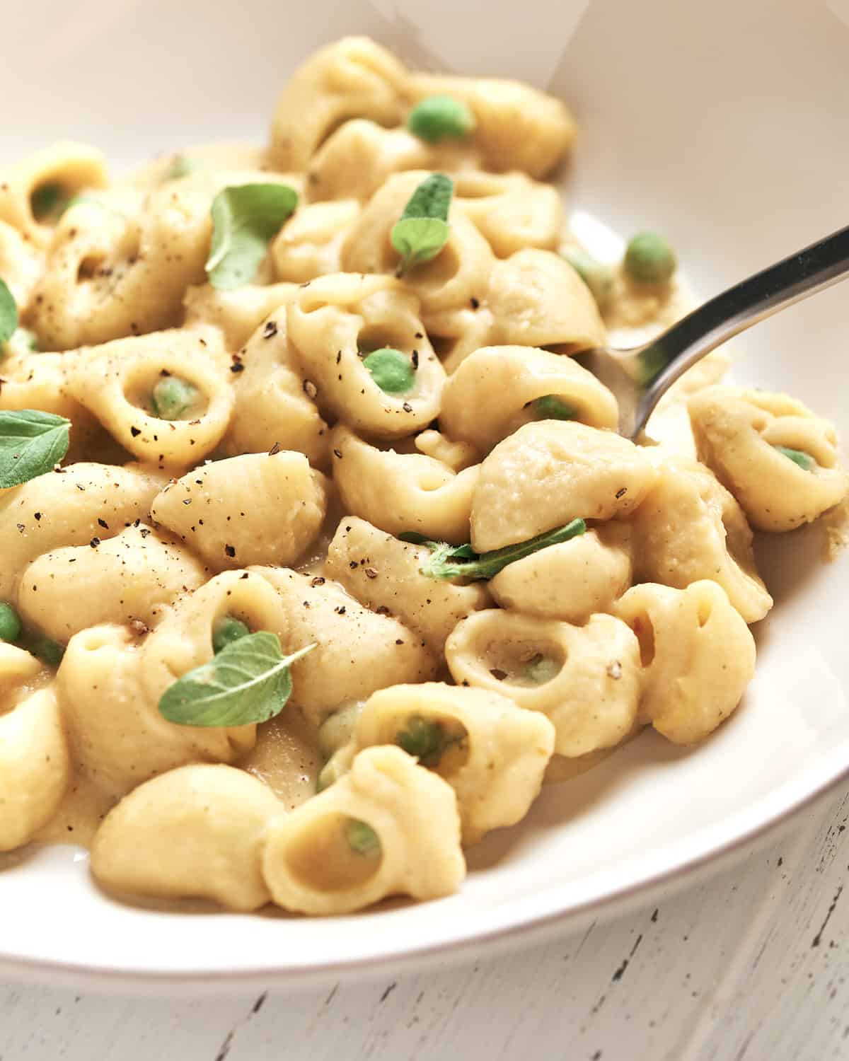 Bowl of creamy vegan pasta with peas.