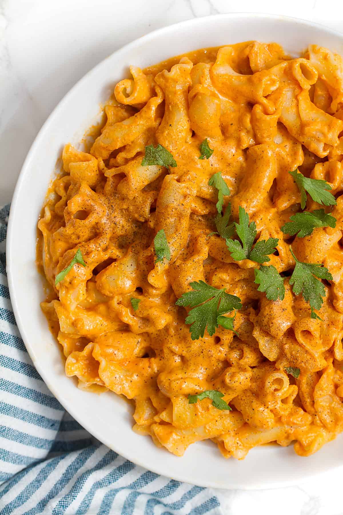 Plate of paprika pasta topped with fresh herbs.