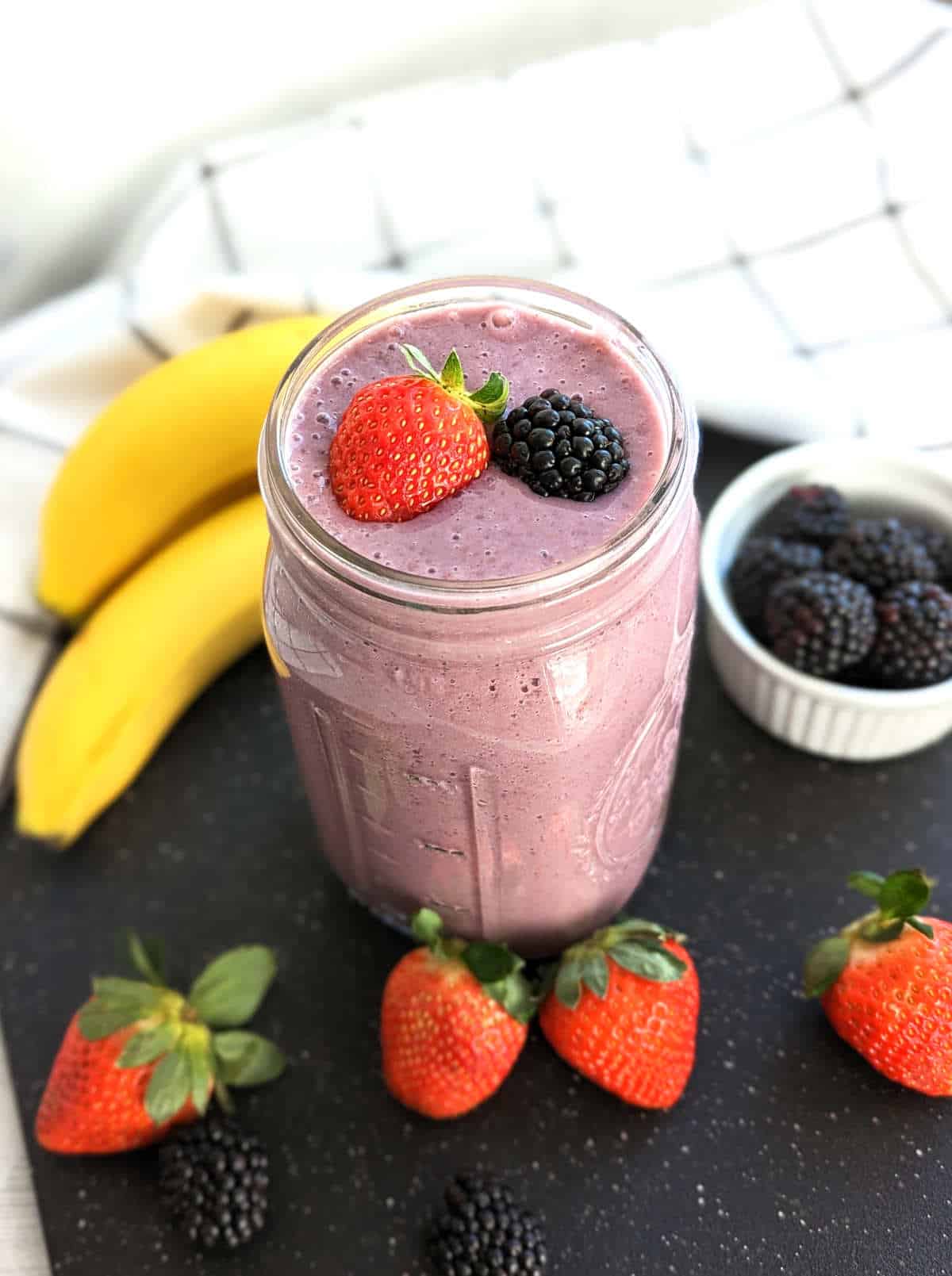 Blackberry strawberry banana smoothie in mason jar topped with fresh berries.