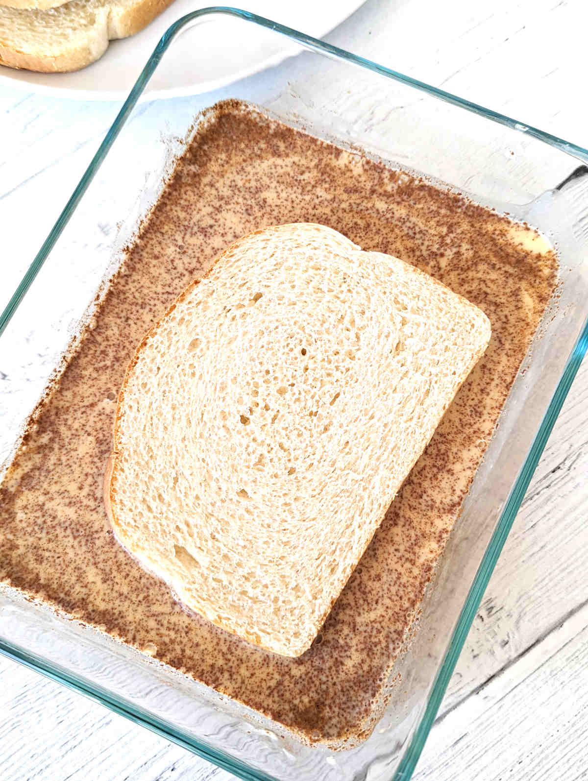 A slice of sourdough bread soaking in the Just Egg batter.