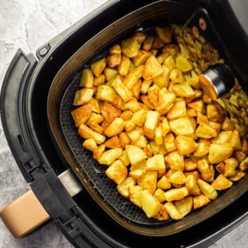 Air fryer basket filled with crispy home fries.