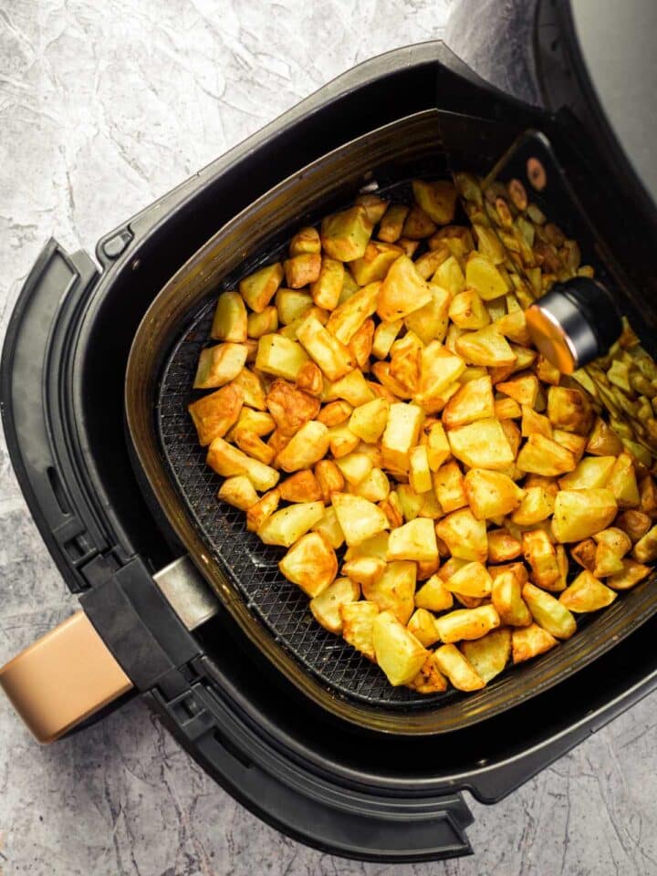 Air fryer basket filled with crispy home fries.