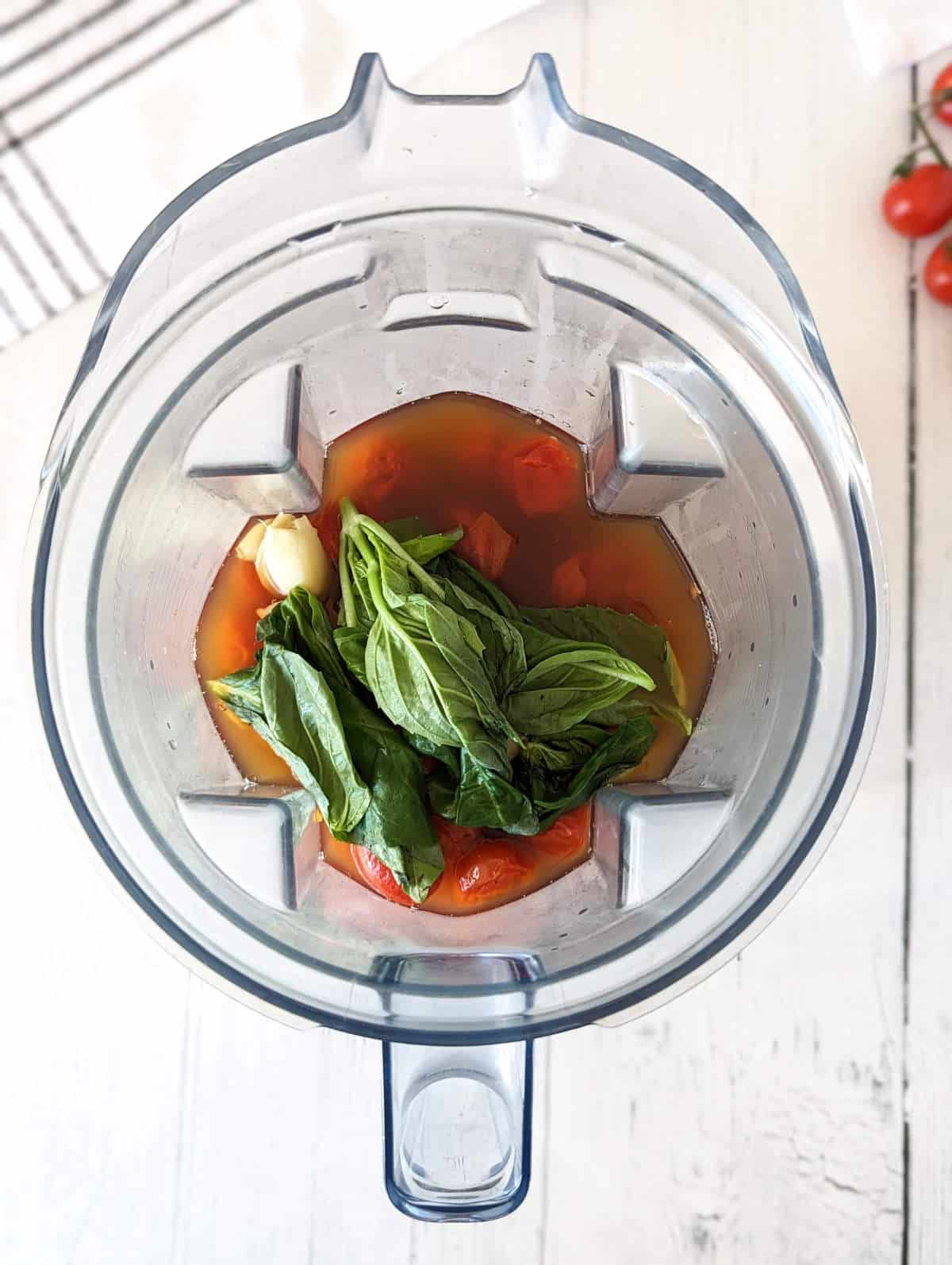 Ingredients for cherry tomato soup in a blender pitcher.