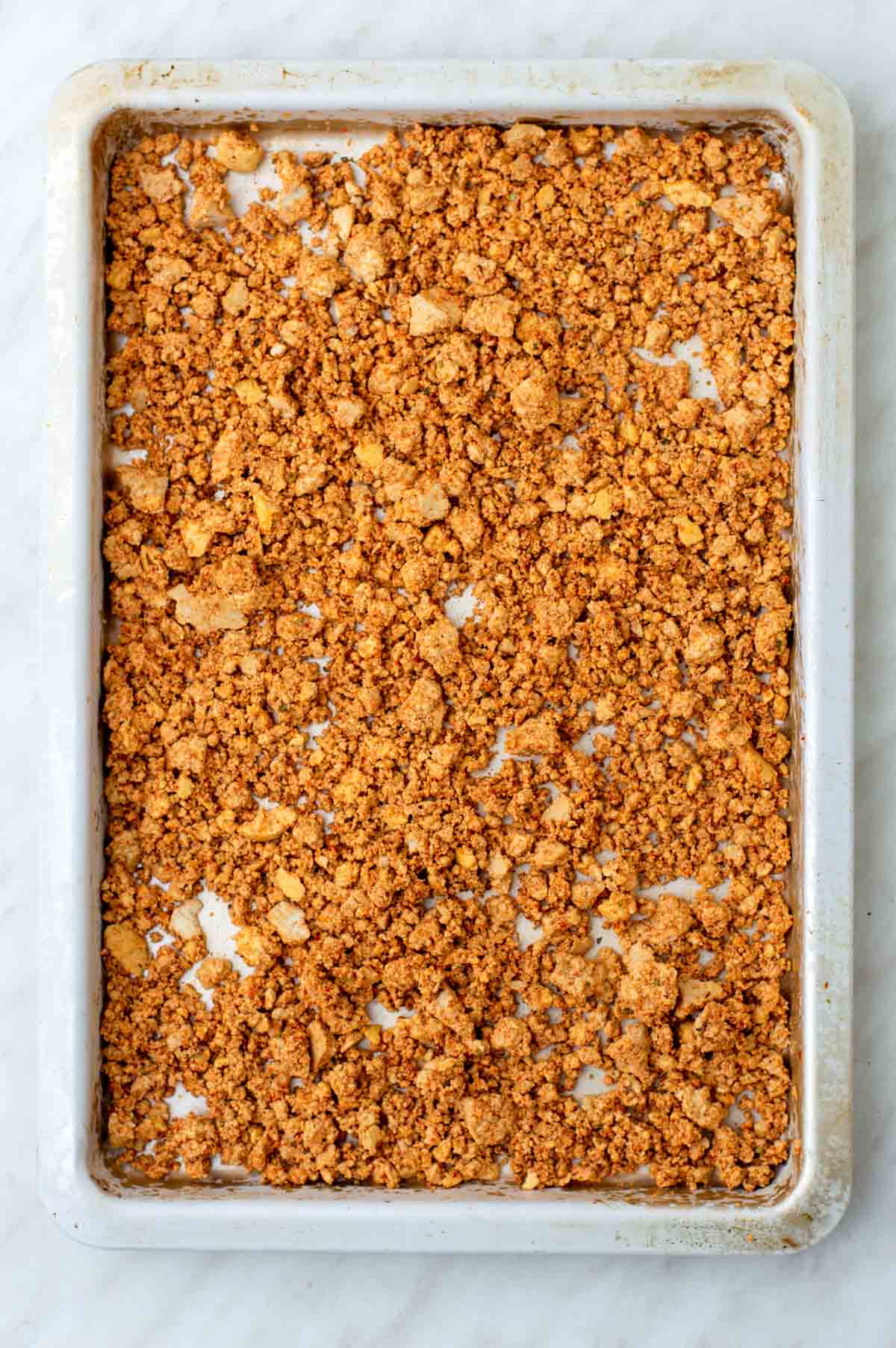 Unbaked tofu crumbles on a baking sheet.
