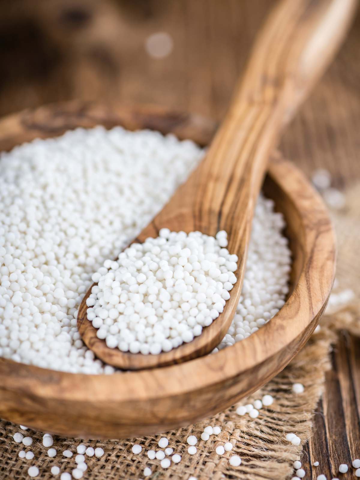 Vegan tapioca pearls in a wooden bowl with a wooden spoon scooping some up.